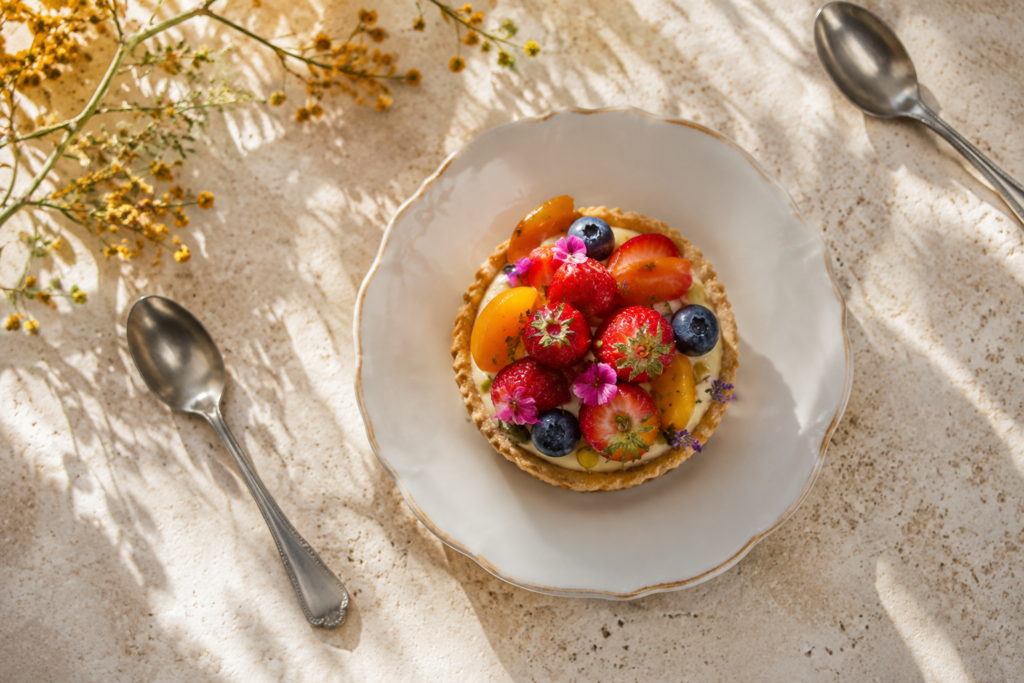 A small fruit tart with dessert spoons
