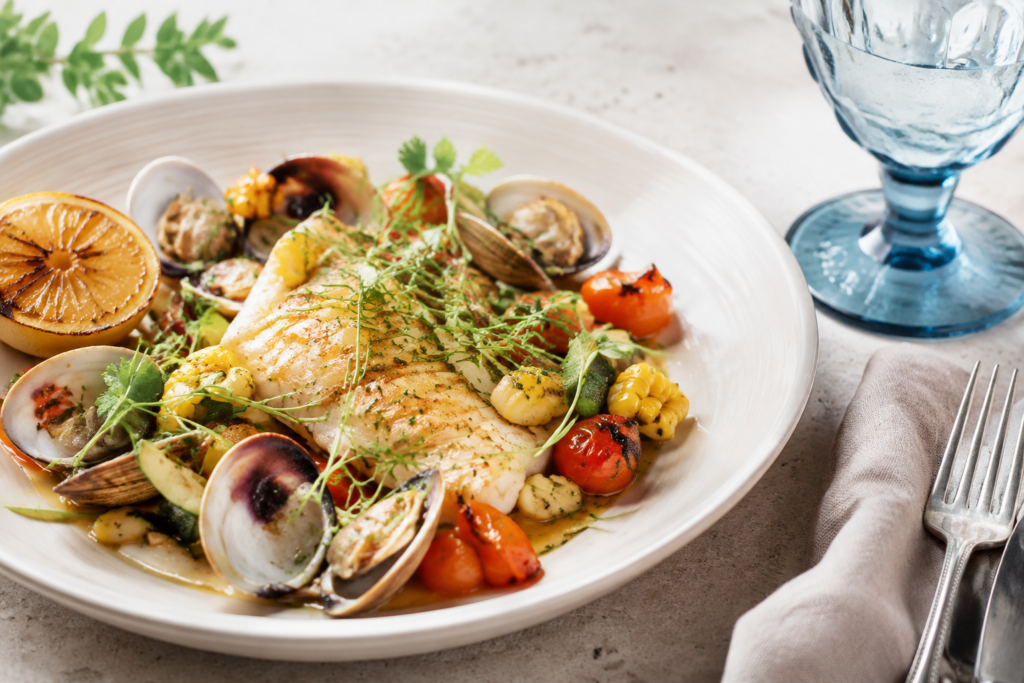 A modern seafood plate with lemon, herbs and vegetables