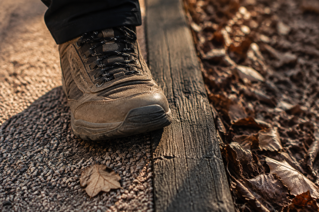 Walking shoe beside gravel and a wooden trail edge — conceptual surface illustration
