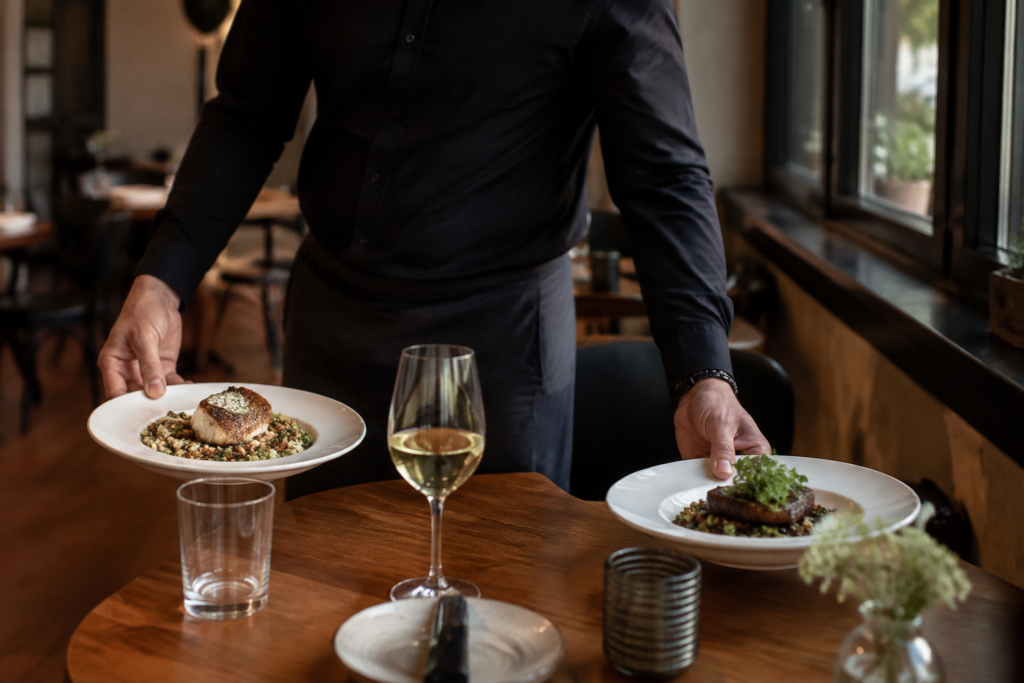 A waiter setting down two appetizing dinner plates for an early evening meal