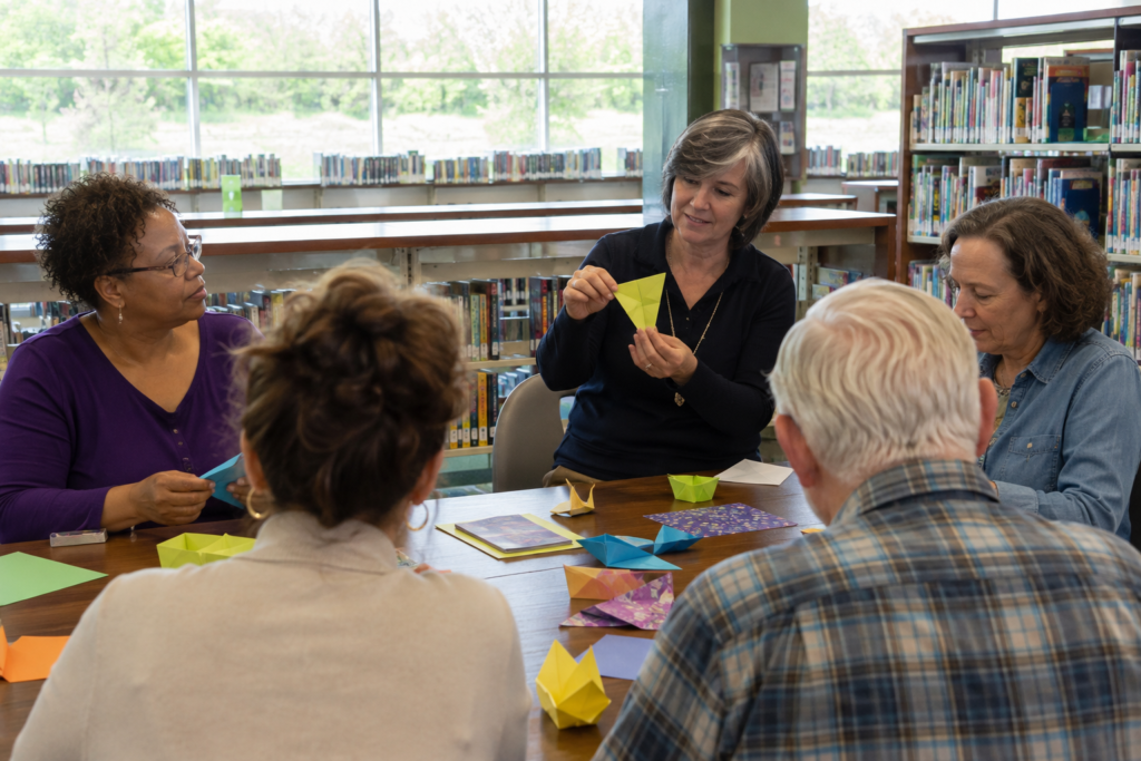 Small adult library workshop making simple paper crafts around a community table