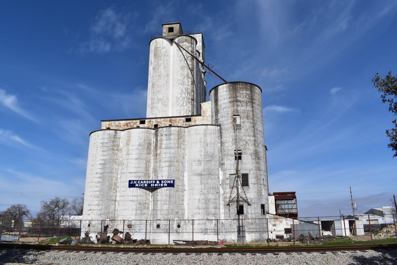 Historic white rice dryer silos beside railroad tracks in Katy, Texas